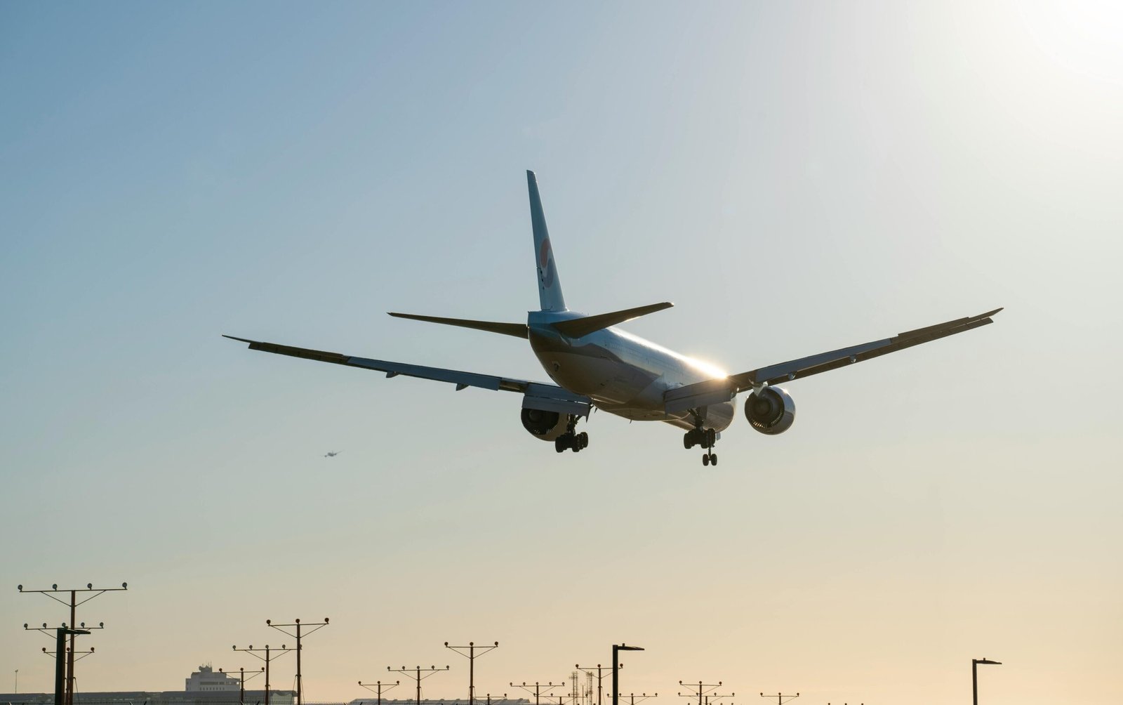 Commercial airplane landing at sunset at Los Angeles Airport, showcasing aviation against a clear sky.